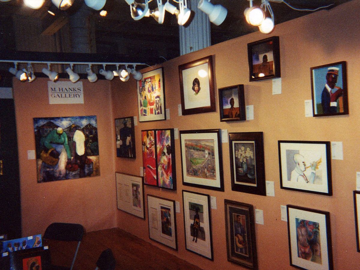 A wall of pictures with lights hanging from the ceiling.
