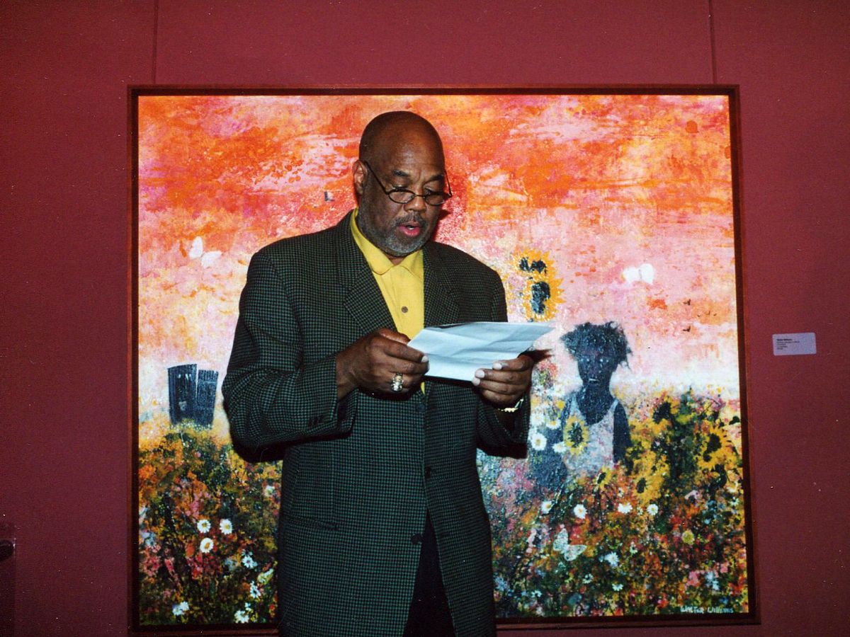 A man standing in front of a painting holding papers.