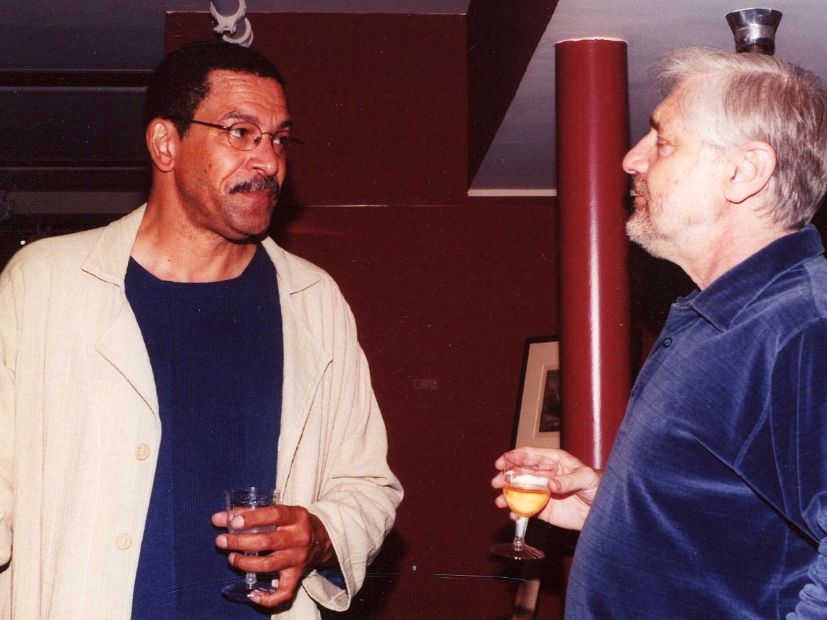 Two men are talking and drinking at a party.