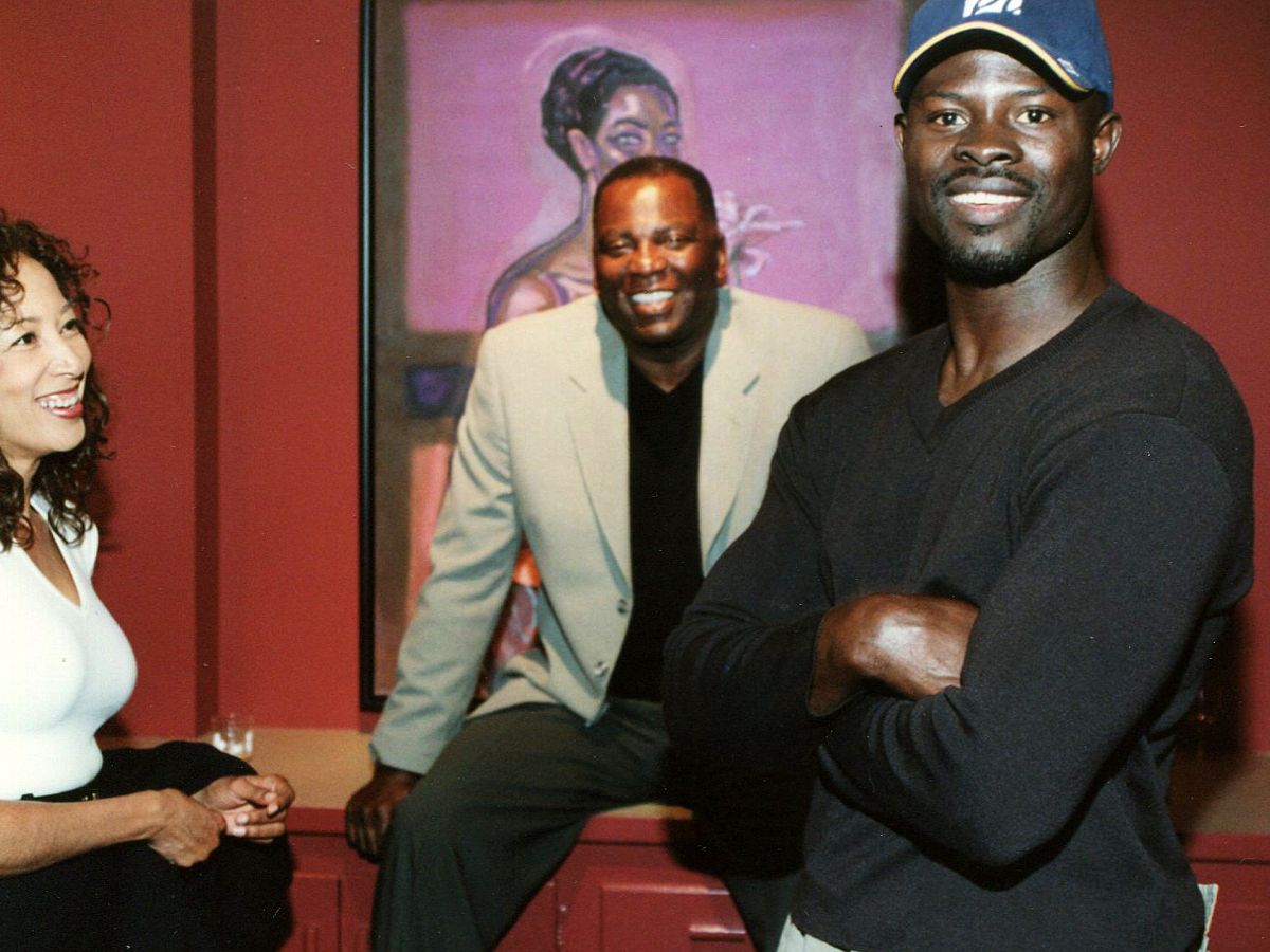 Two men posing for a picture in front of a painting.