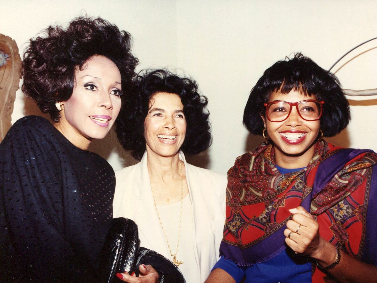 Three women standing next to each other in a room.