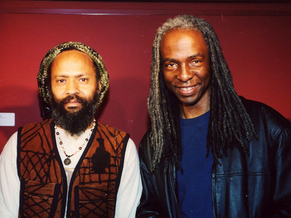 Two men with long hair and dreadlocks are posing for a picture.