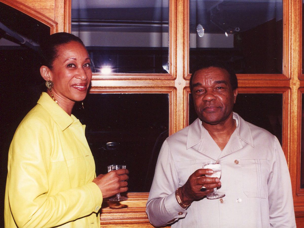 A man and woman holding drinks in front of a window.