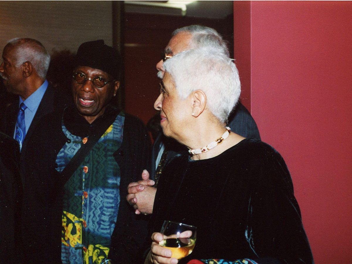 Two people standing next to each other holding drinks.